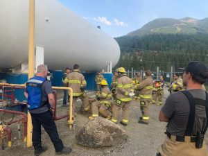 Fire and utilities personnel congregate outside around propane tank for training.